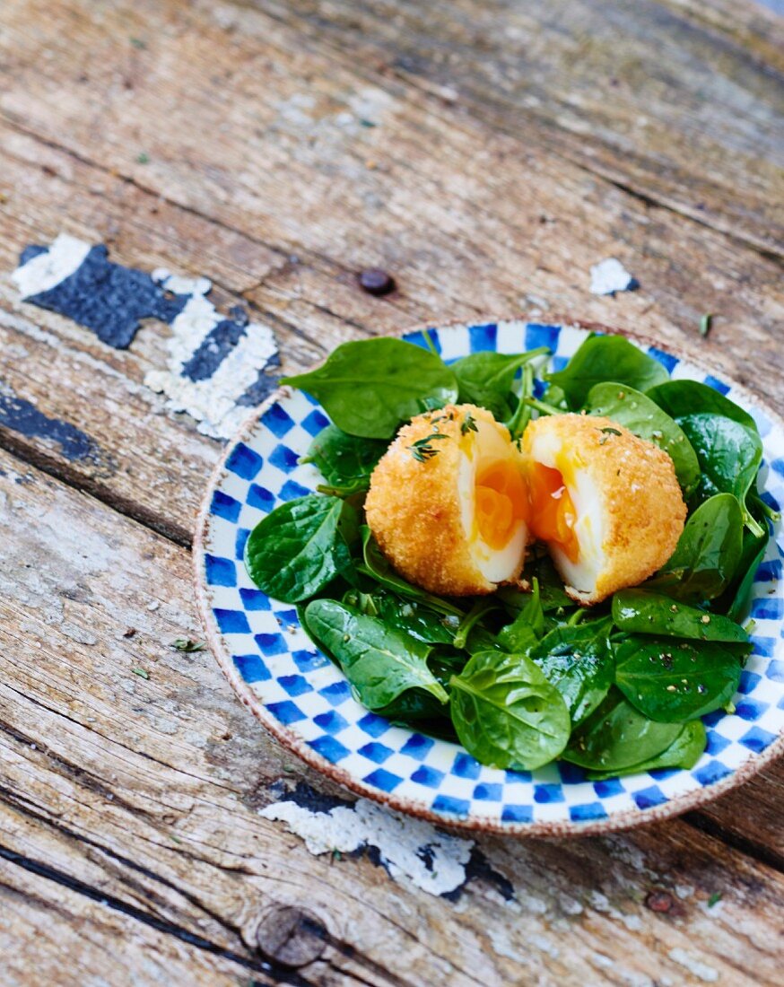 Breaded soft-boiled egg with raw baby spinach