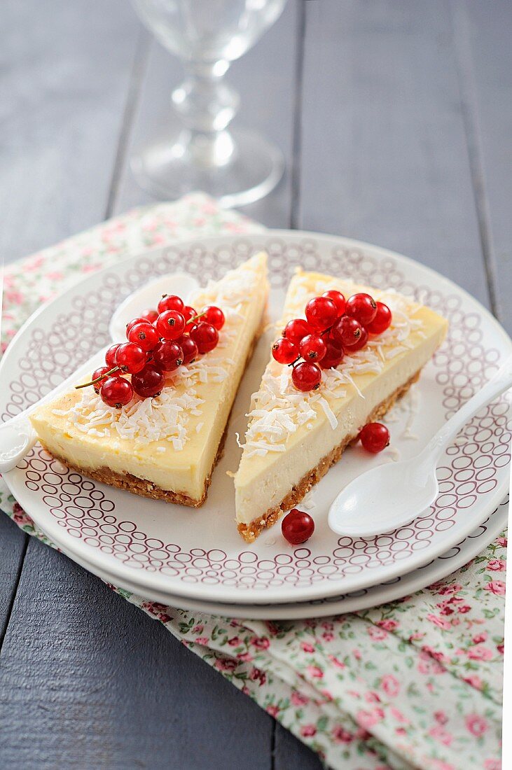 Two pieces of cheesecake with coconut and red currants