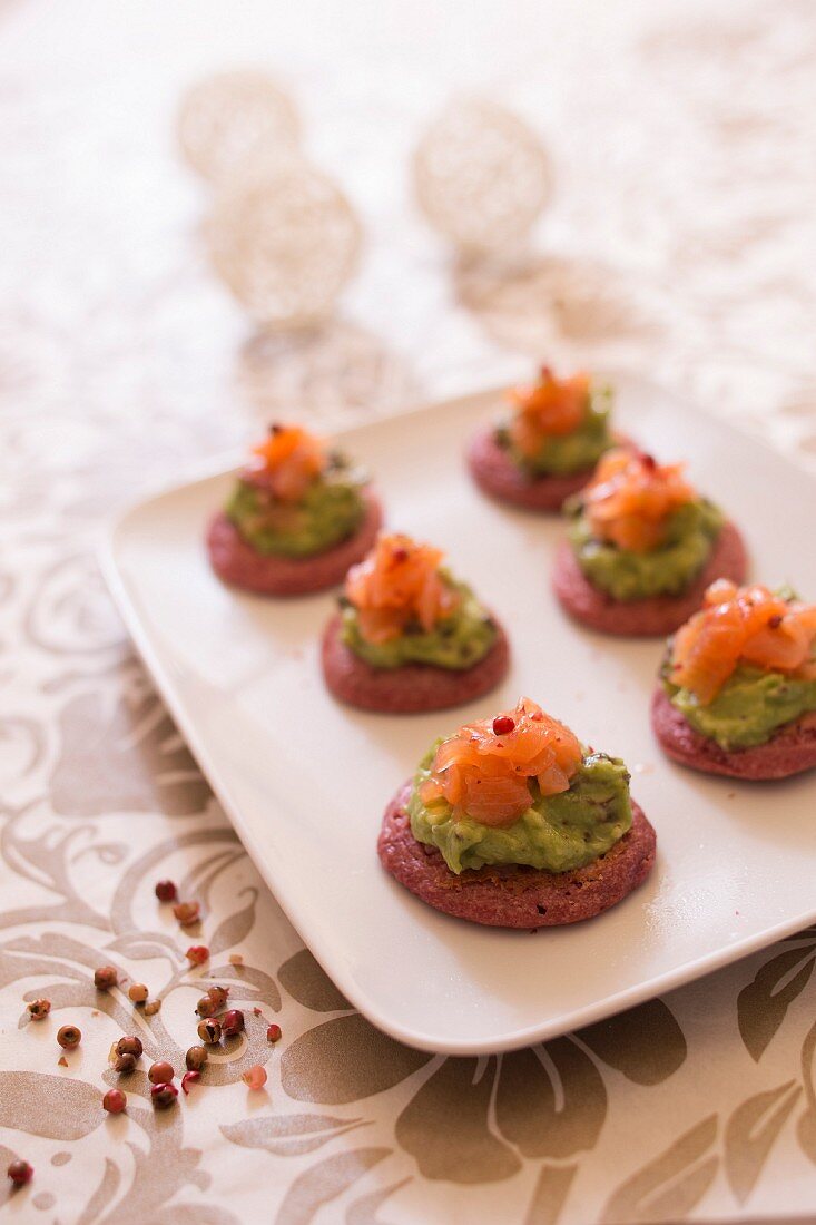 Beetroot blinis garnished with guacamole and smoked salmon