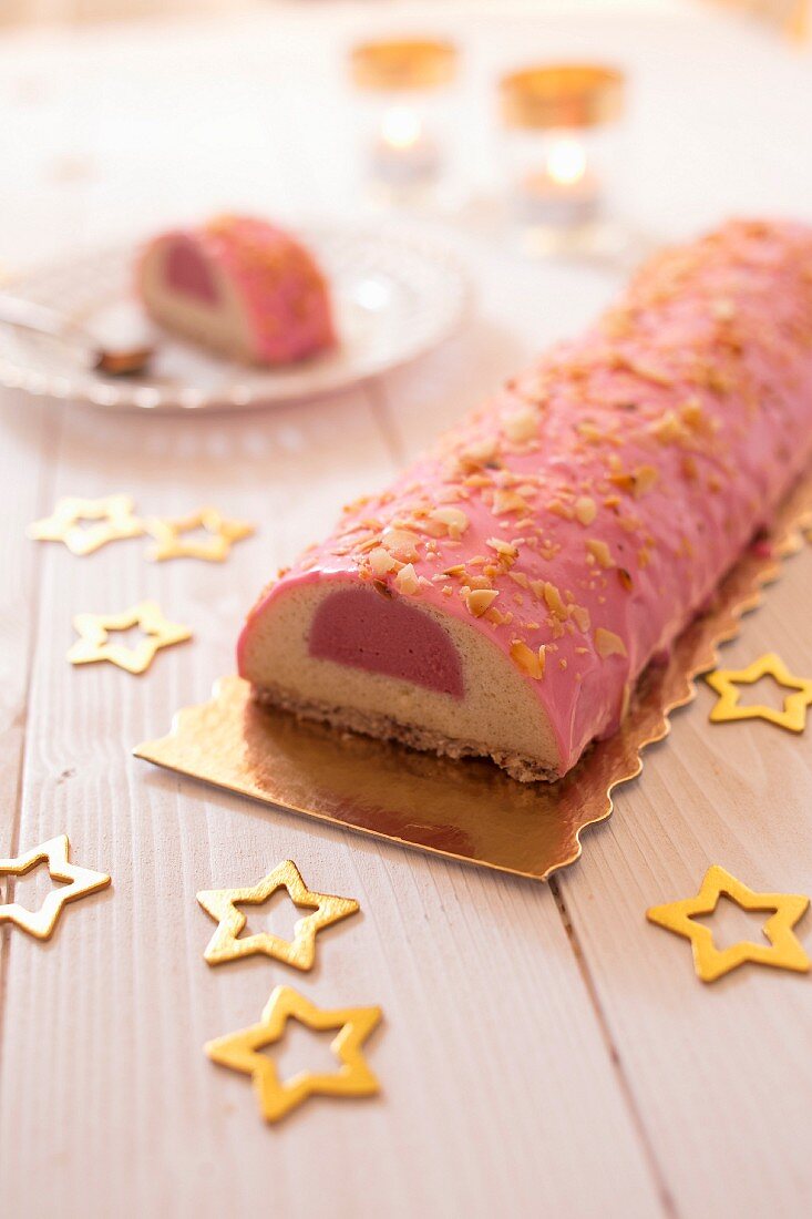 Vanilla-raspberry Chritmas log cake coated with pink icing