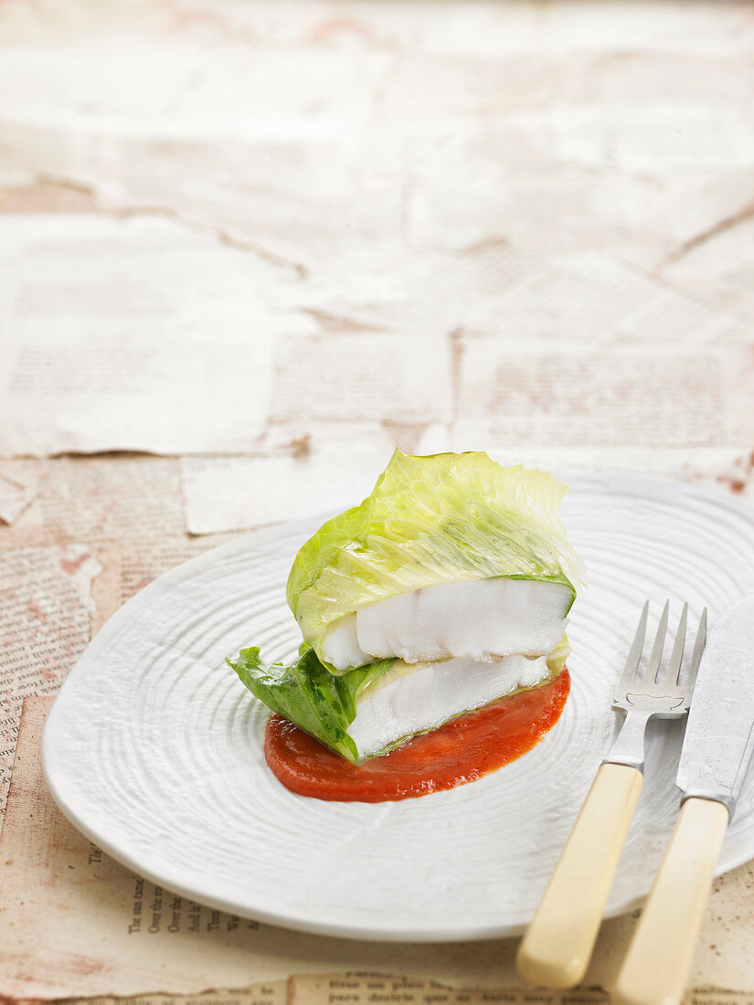 Bass fillets wrapped in lettuce leaves on a bed of homemade ketchup