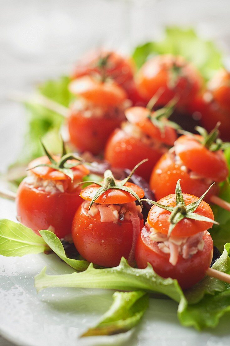 Small tomatoes stuffed with raw ham and button mushrooms on skewers