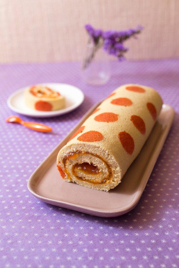 Apricot jam rolled sponge cake decorated with orange spots