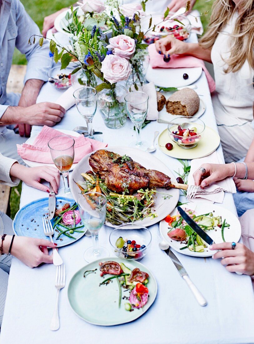 Gäste sitzen beim Essen an einem Tisch im Freien