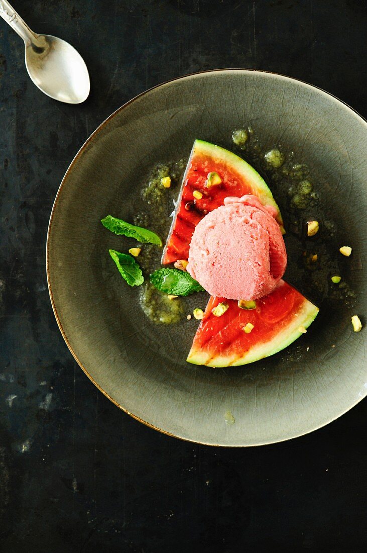 Gegrillte Wassermelone mit Kugel Erdbeer-Joghurt-Eiscreme, Orangensauce, Honig und Pistazien