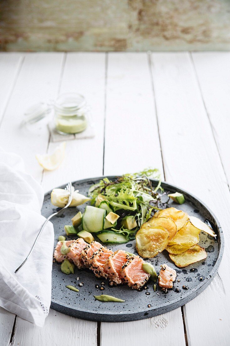 Salmon tataki with a sesame seed crust and wasabi cream, chips and a cucumber and avocado salad