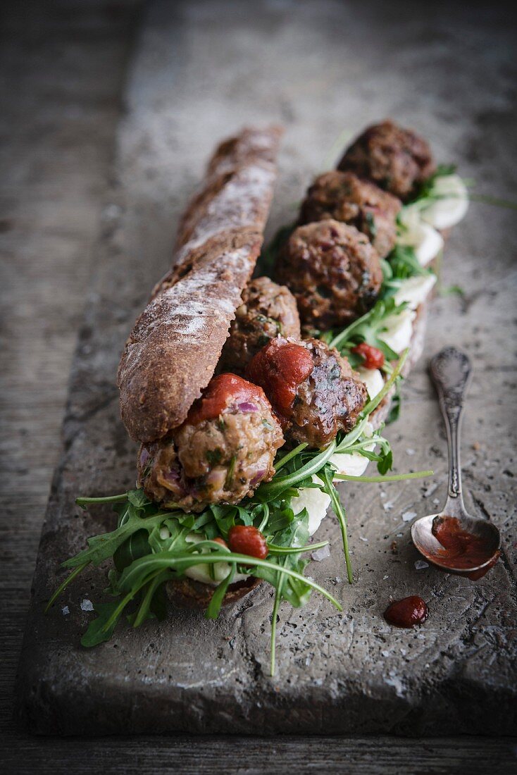 Wholemeal baguette with meatballs, ketchup, rocket and cheese