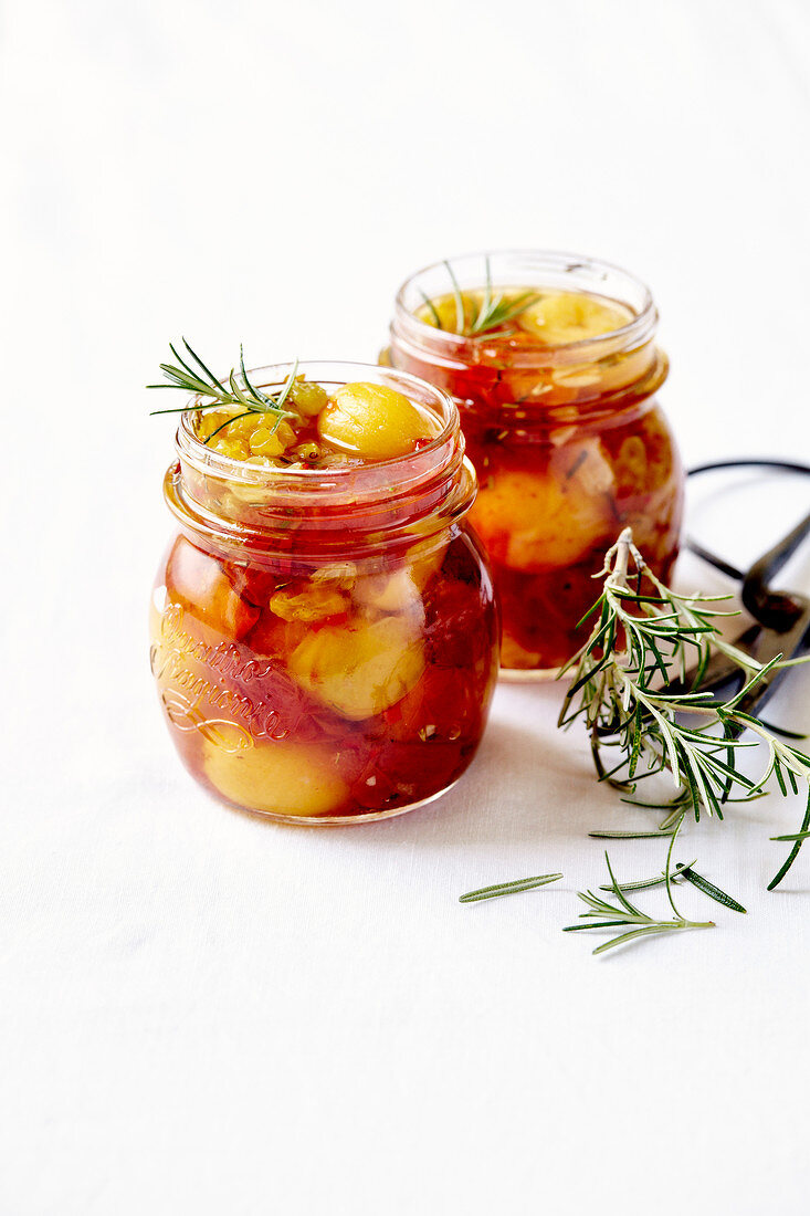Preserved yellow plums with tomatoes, sultanas and rosemary in preserving jars