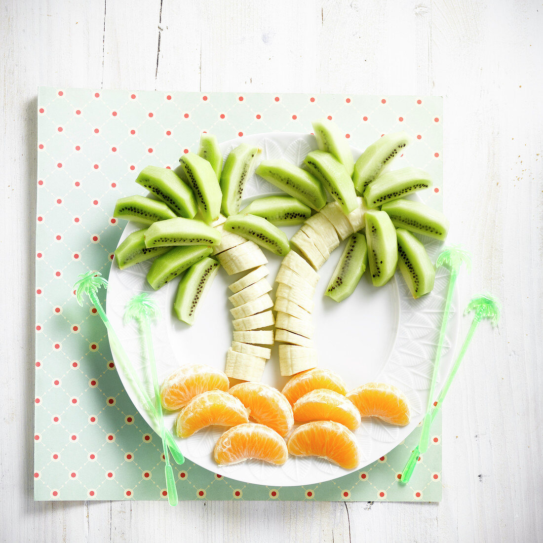 Aufgeschnittene Mandarinen, Bananen und Kiwis in Palmenform