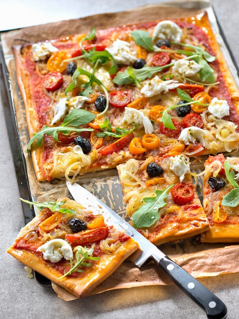 Pizza mit Zwiebelconfit, marinierten Tomaten, Rucola und Mozzarella