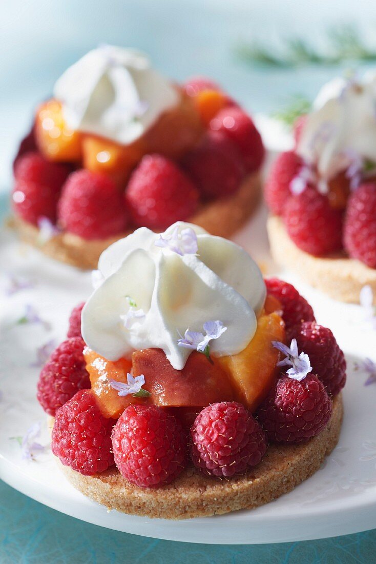 Raspberry,peach and whipped cream tartlets with rosemary flowers