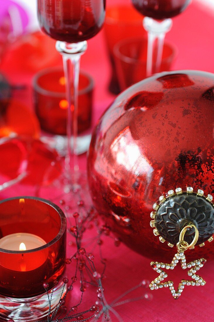 Rote Weihnachtsdeko mit Christbaumkugel und Teelicht