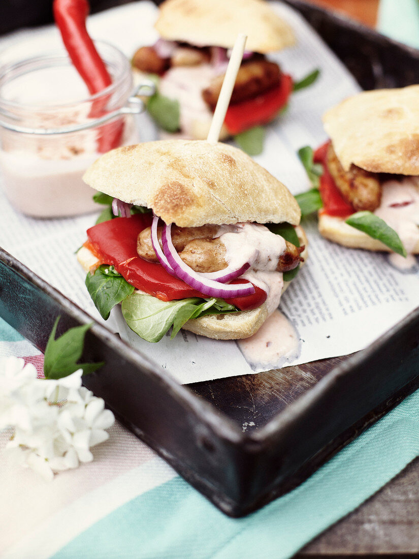 Kleine Ciabatta-Sandwiches mit Geflügelwürstchen, Paprika, Spinat und Zwiebeln