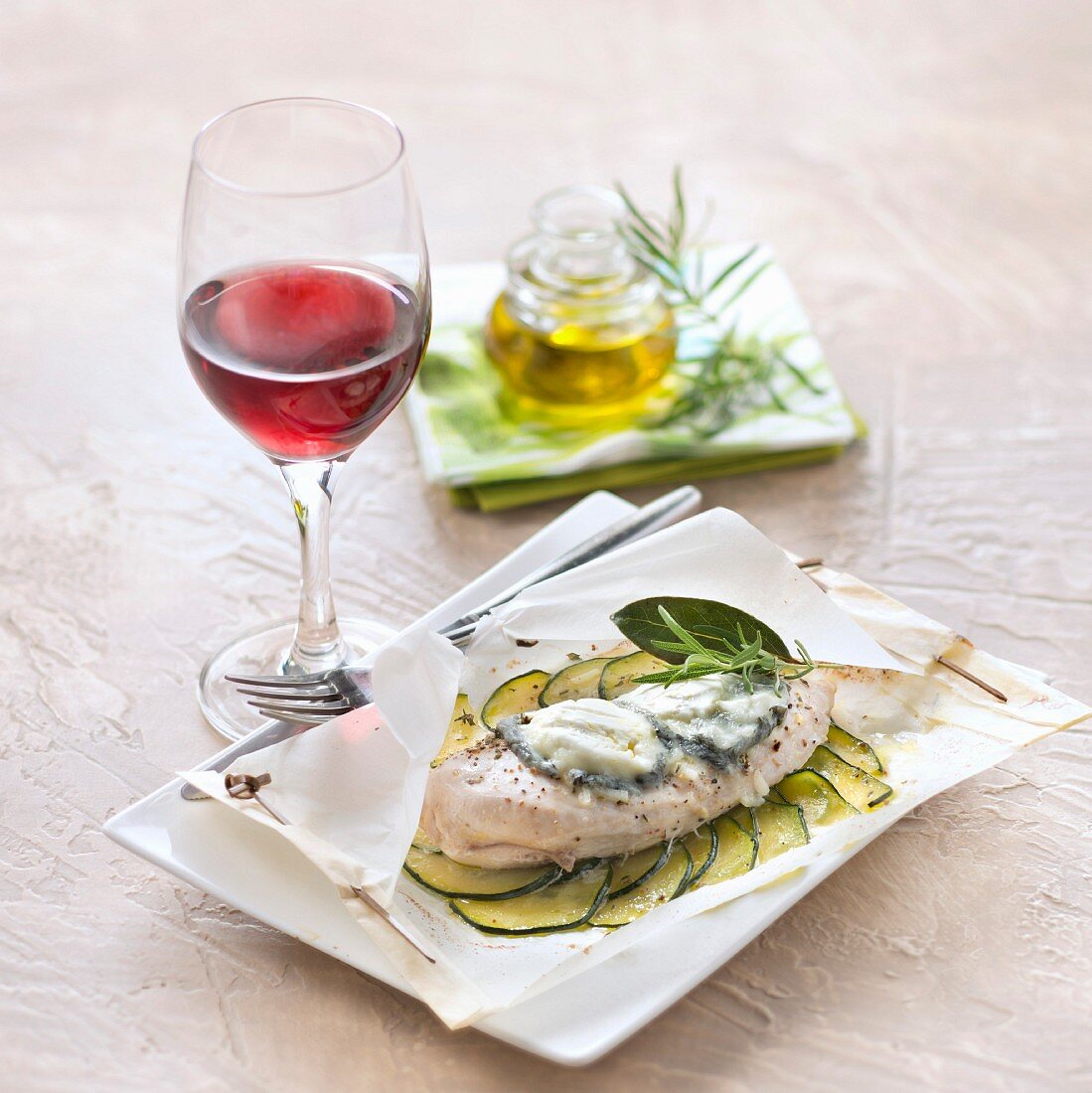 Hähnchenbrust mit Zucchini und Rosmarin im Pergamentpapier und ein Glas Rotwein