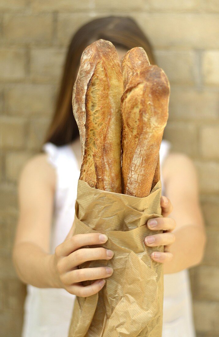 Young girl holding 3 baguettes