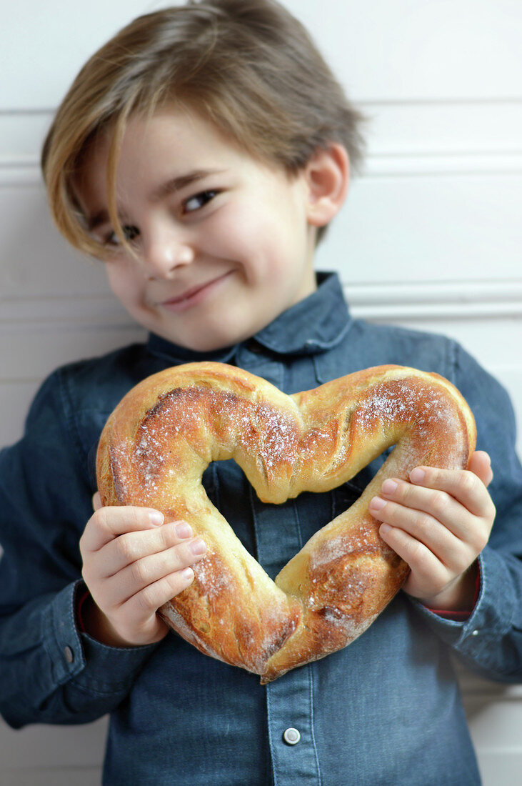 Child holding a heart-shaped bread