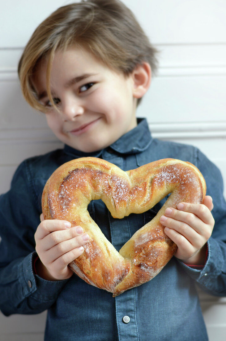 Kind umarmt ein herzförmiges Brot