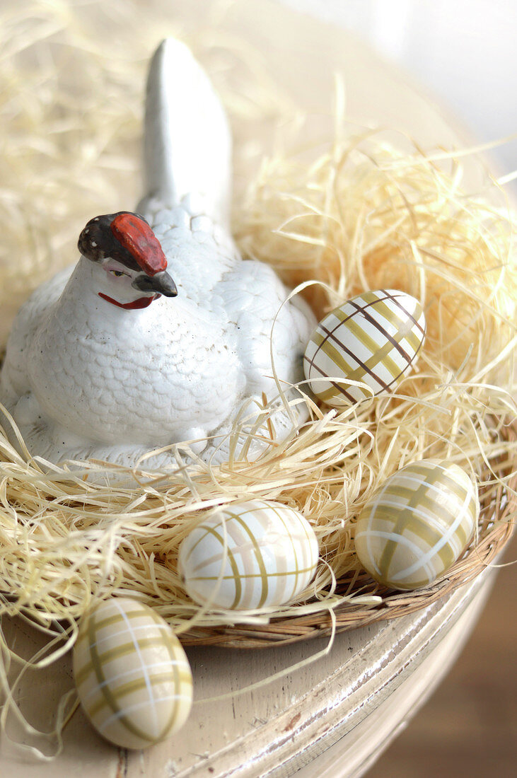 Decorated Easter eggs and a china hen in a raffia nest