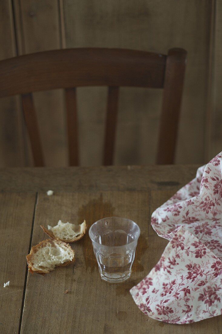 Brotkrümel und Glas auf einem Holztisch