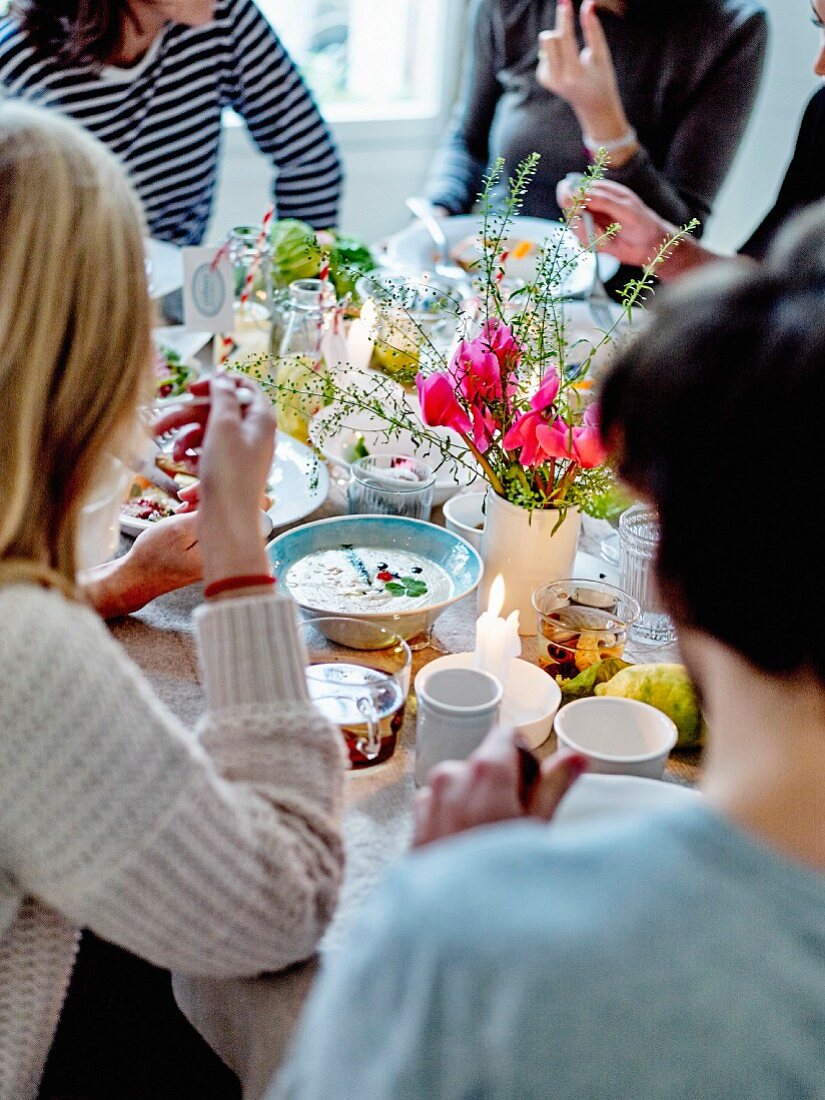 Gäste sitzen am gedeckten Tisch mit Essen