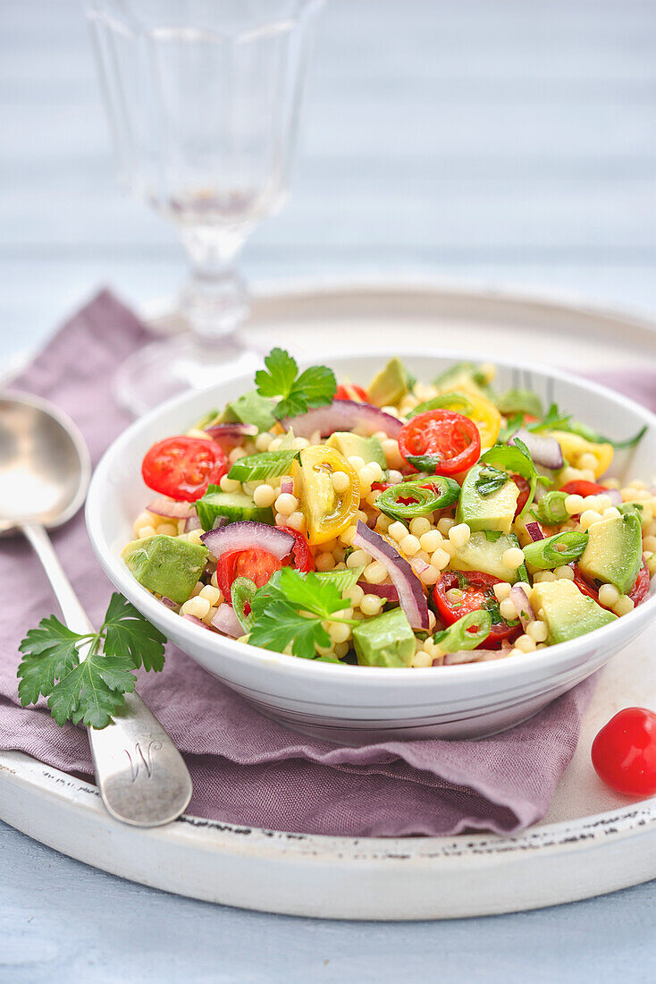 Pearl salad with avocado, two tomatoes and red onion