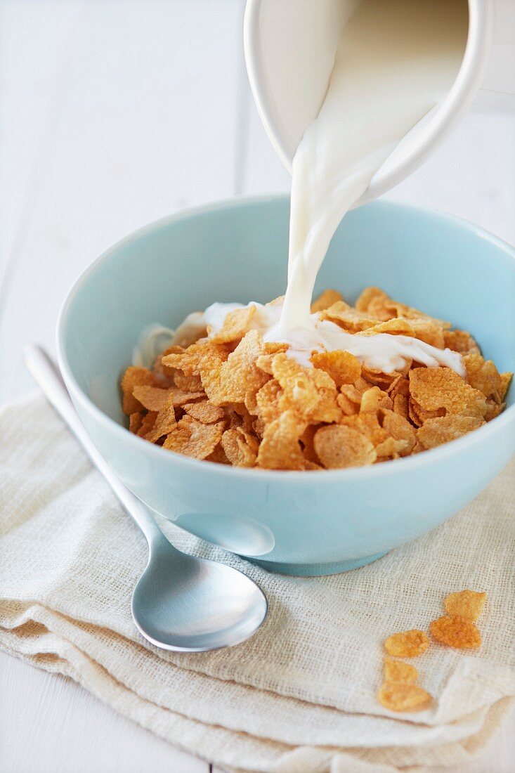 Milch über Cornflakes gießen