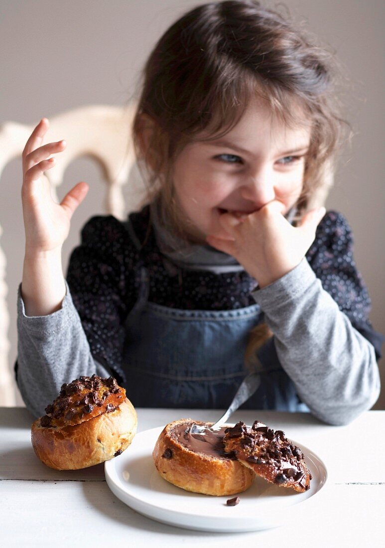 Young girl smiling in front of a brioche with chocolate filling