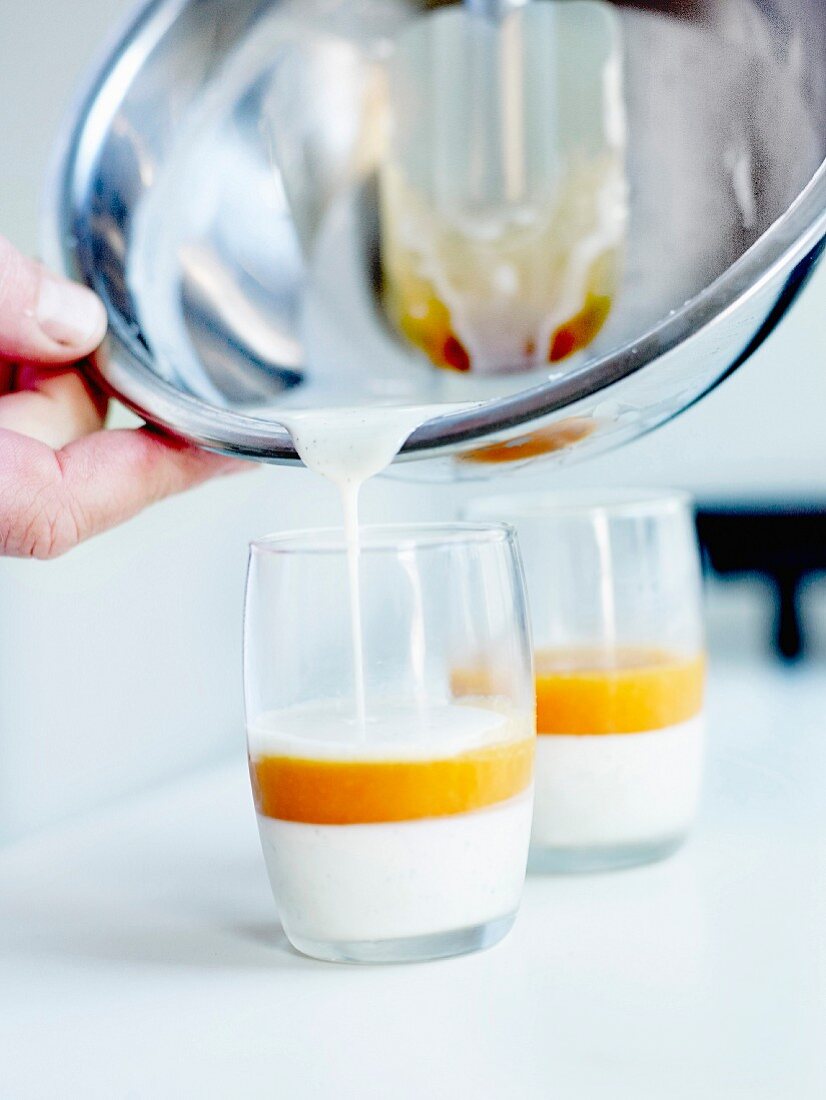 Pouring a layer of vanilla-flavored liquid cream on the apricot pulp in the glasses