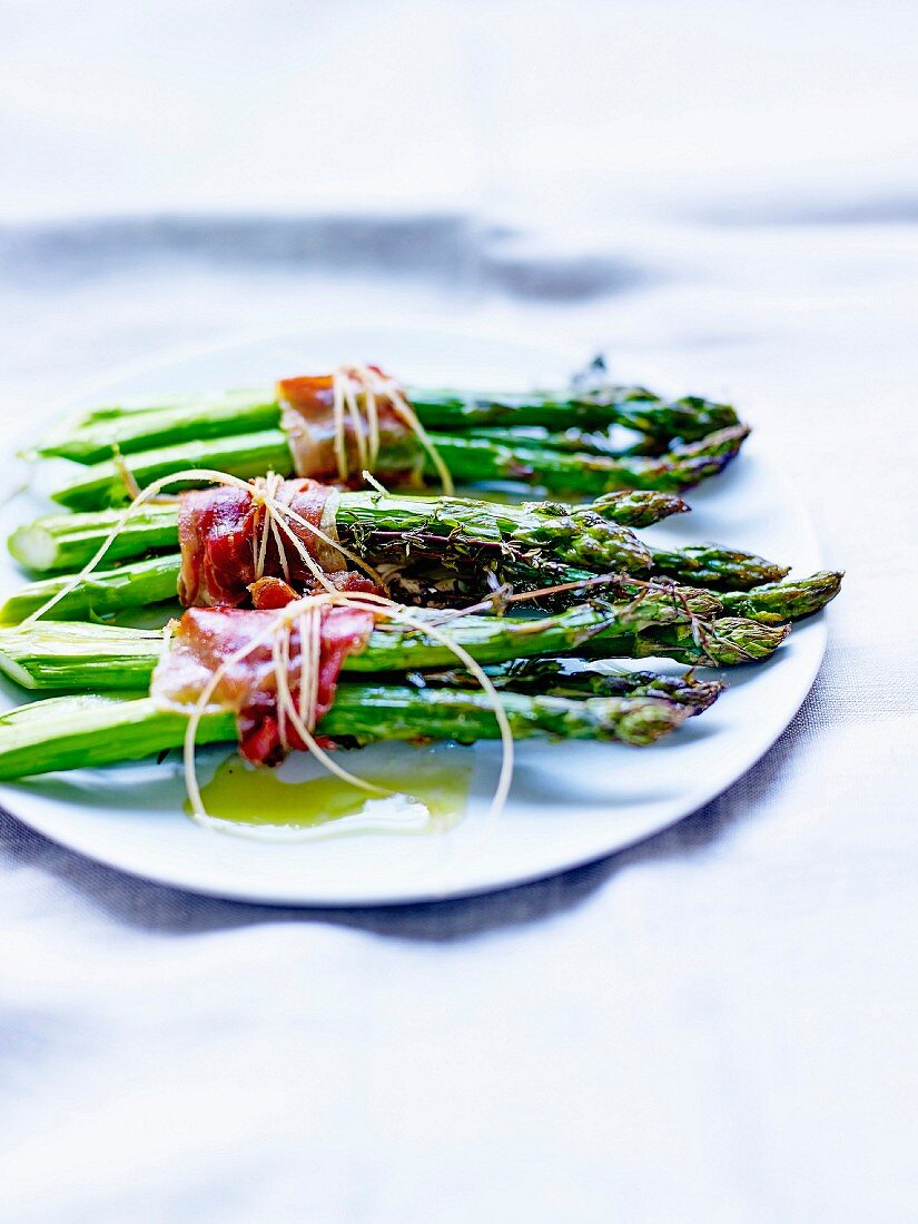 Bundles of green asparagus with anchovies, smoked bacon and thyme