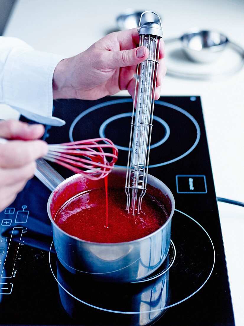 Dipping a thermometer in the preparation to check the temperature while cooking