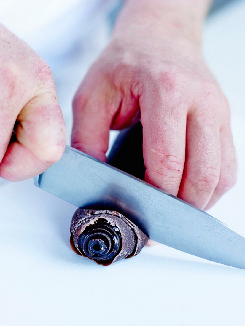 Lakritze herstellen: Mit einem Messer die Lakritzenwurst in Scheiben schneiden