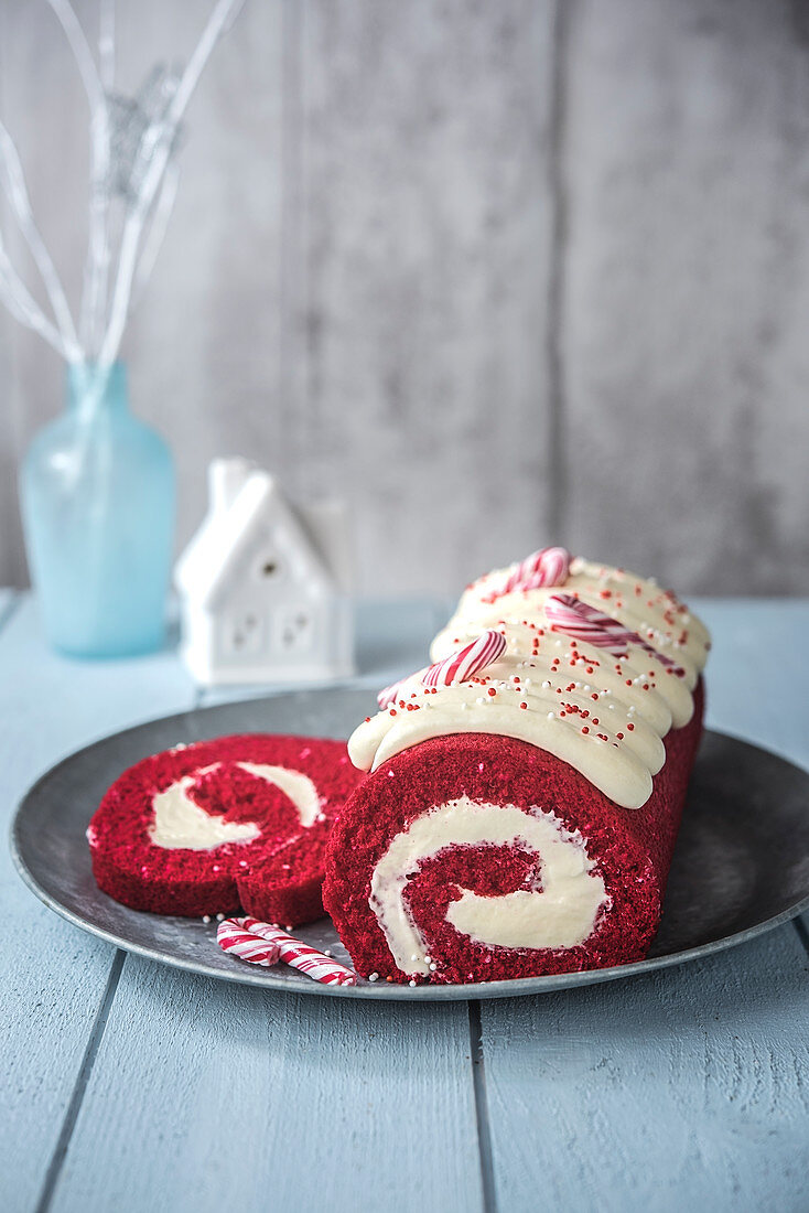 Red sponge cake roll with cream filling and candy canes (Christmas)