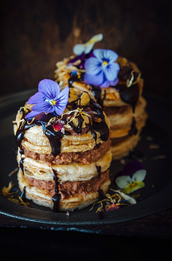 Geschichtete Käsetörtchen mit Nutella-Mousse, dunkler Schokosauce und Blüten