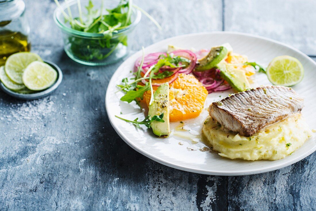 Roasted fish fillet, iime-flavored mashed potatoes, orange fruit salad, red onions, rocket lettuce and avocado