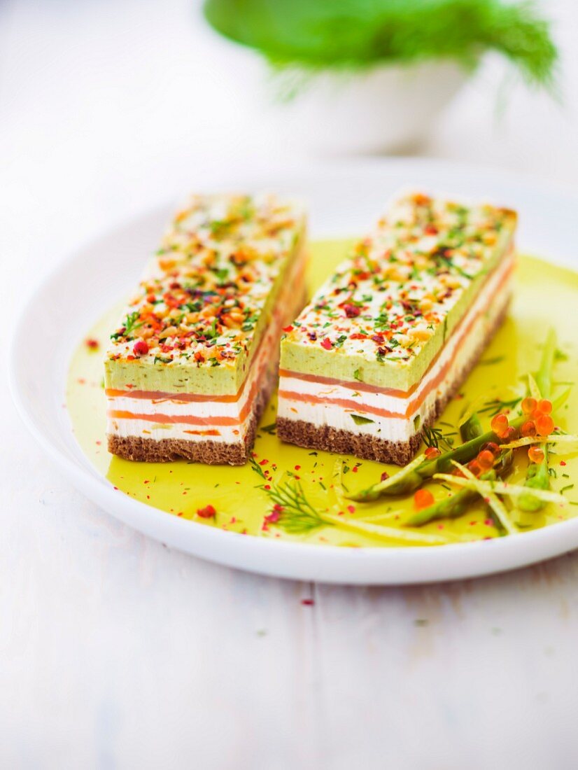 Smoked salmon, pesto, fromage frais and spring vegetable layer on white bread and decorated with almonds, red pepper and parsley