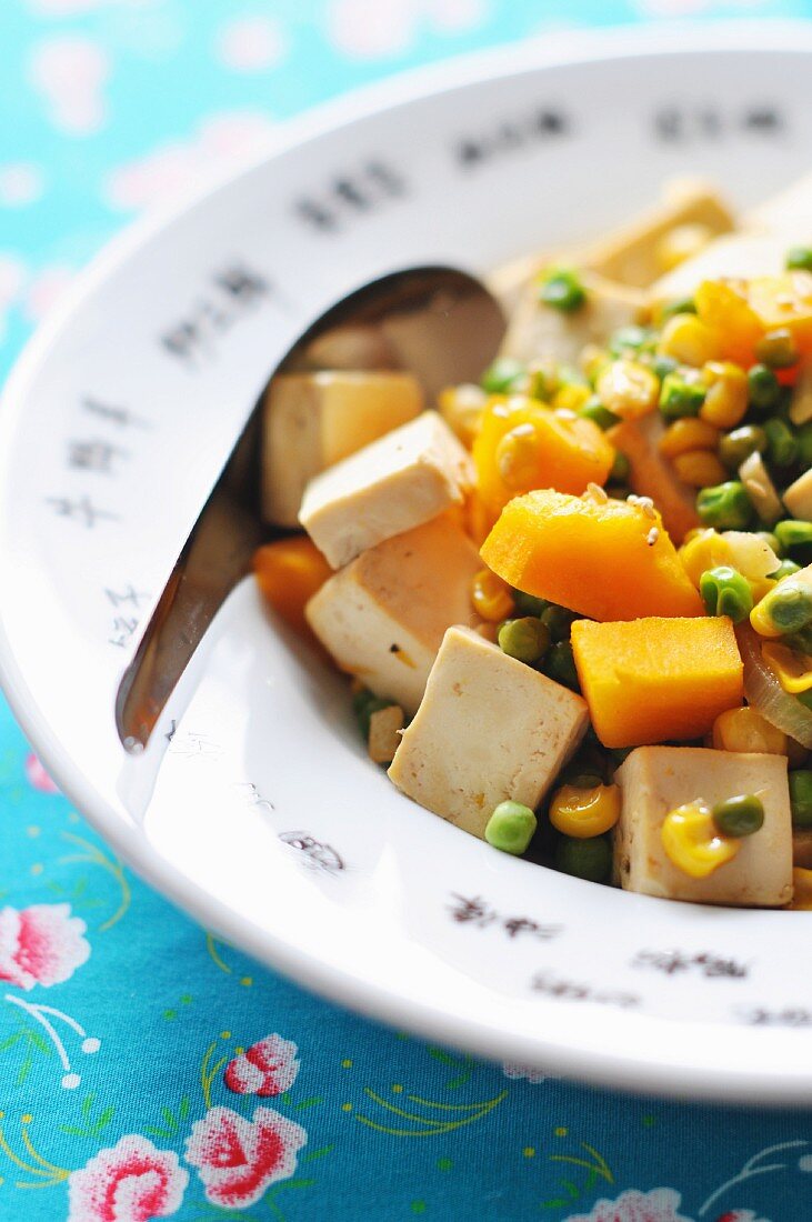 Grüne Erbsen mit Tofu, Mais und gebratenem Kürbis auf asiatische Art