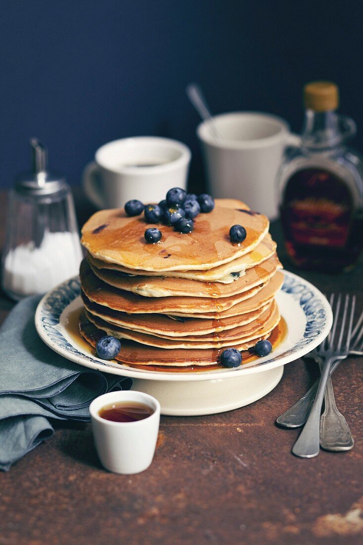 Pile of pancakes with maple syrup and blueberries