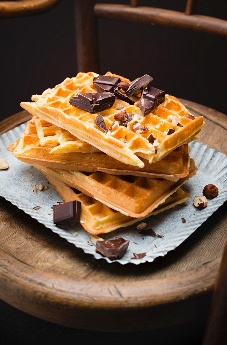 Pile of Brussels waffles, squares of dark chocolate and hazelnuts