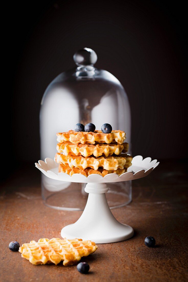 Pile of waffles Liégeoises, blueberries and a glass dome