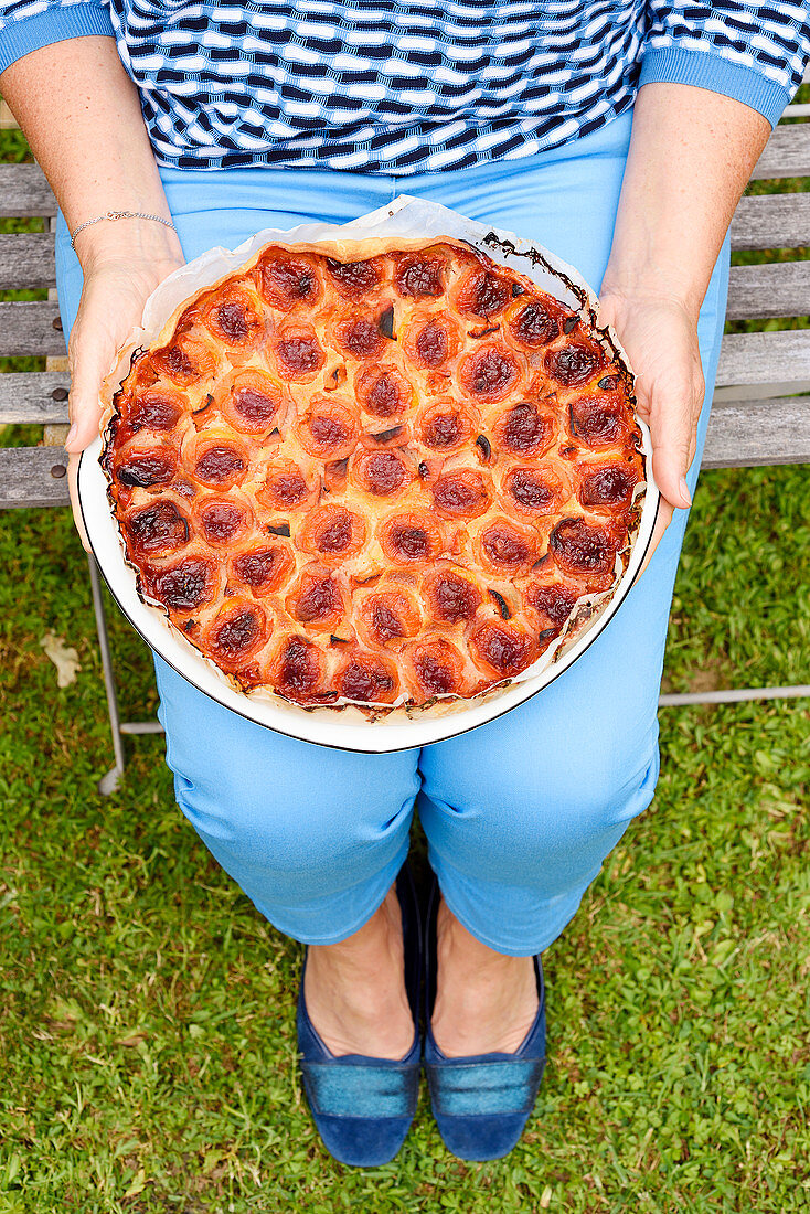 Woman holding apricot tart (vegetarian)