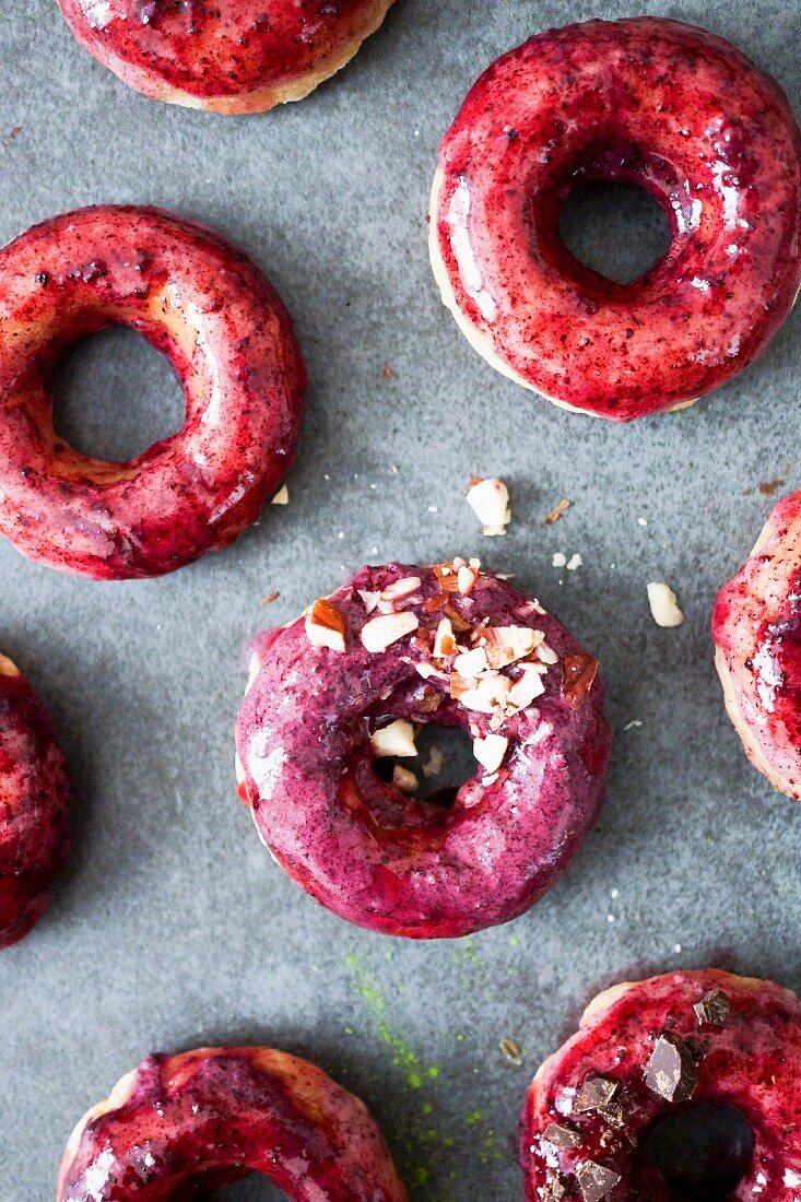 Pile of green tea and blackcurrant donuts topped with crushed almonds and chocolate