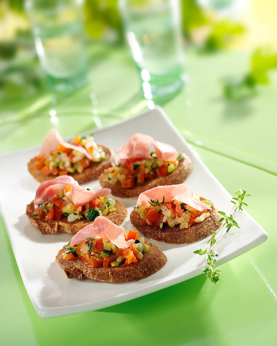 Diced vegetable and thin strips of raw ham crostinis