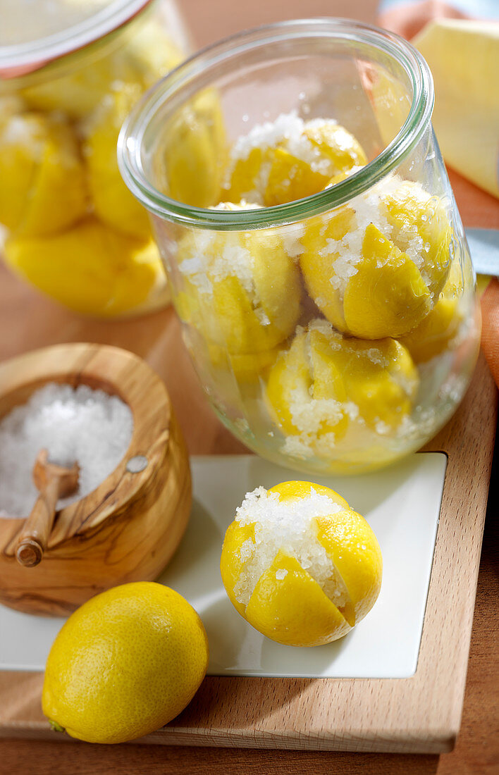 Placing lemons in a jar with salt to prepare confit citrus