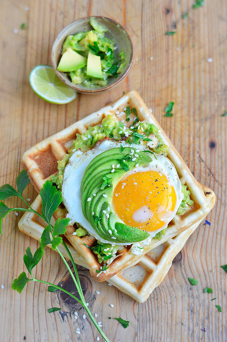 Potato waffles with guacamole, fried egg and sliced avocado