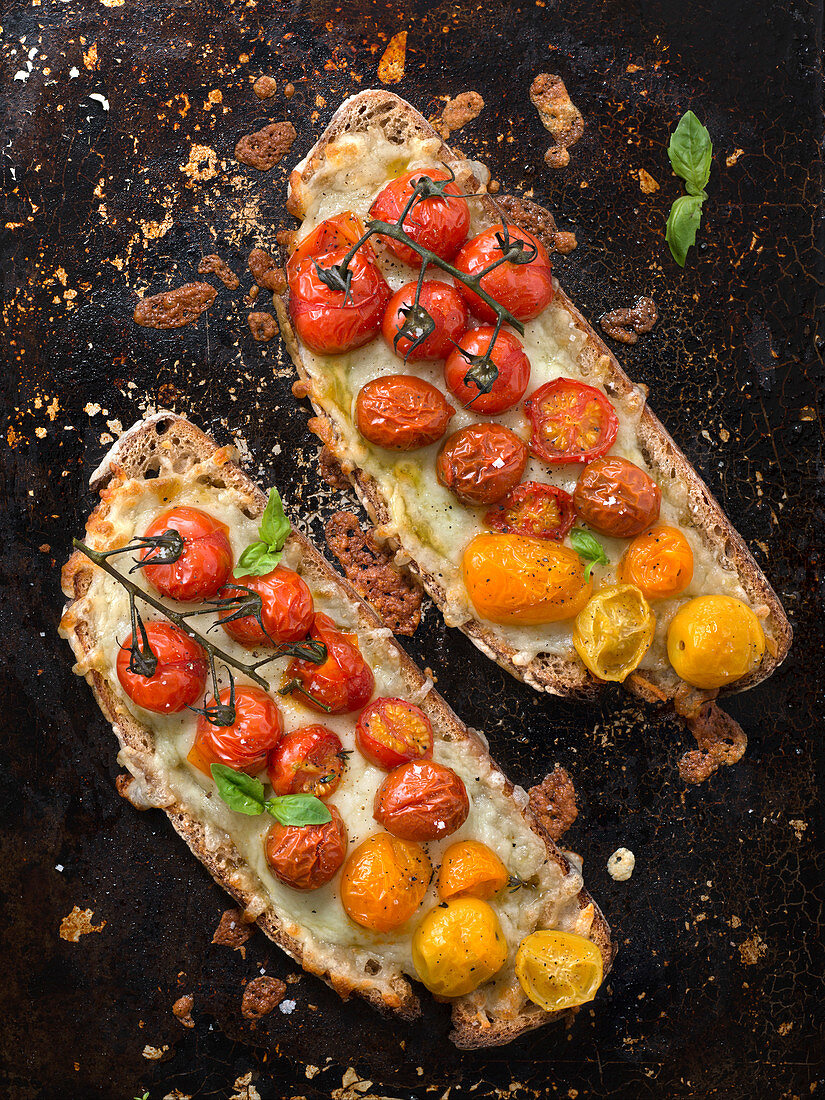 Belegte Brote mit Mozzarella, roten und gelben Kirschtomaten und Basilikum