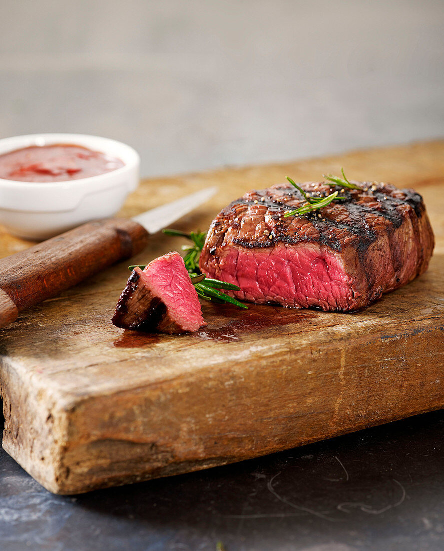 Grilled beef steak sliced on a wooden chopping board