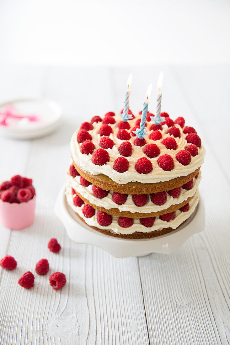 Coconut-raspberry layer cake with birthday candles