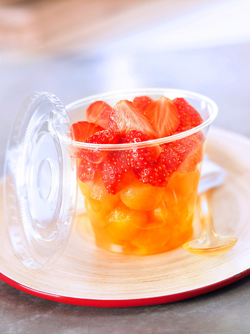 Fruchtsalat mit Erdbeeren und Melonenbällchen im Take-Away-Becher
