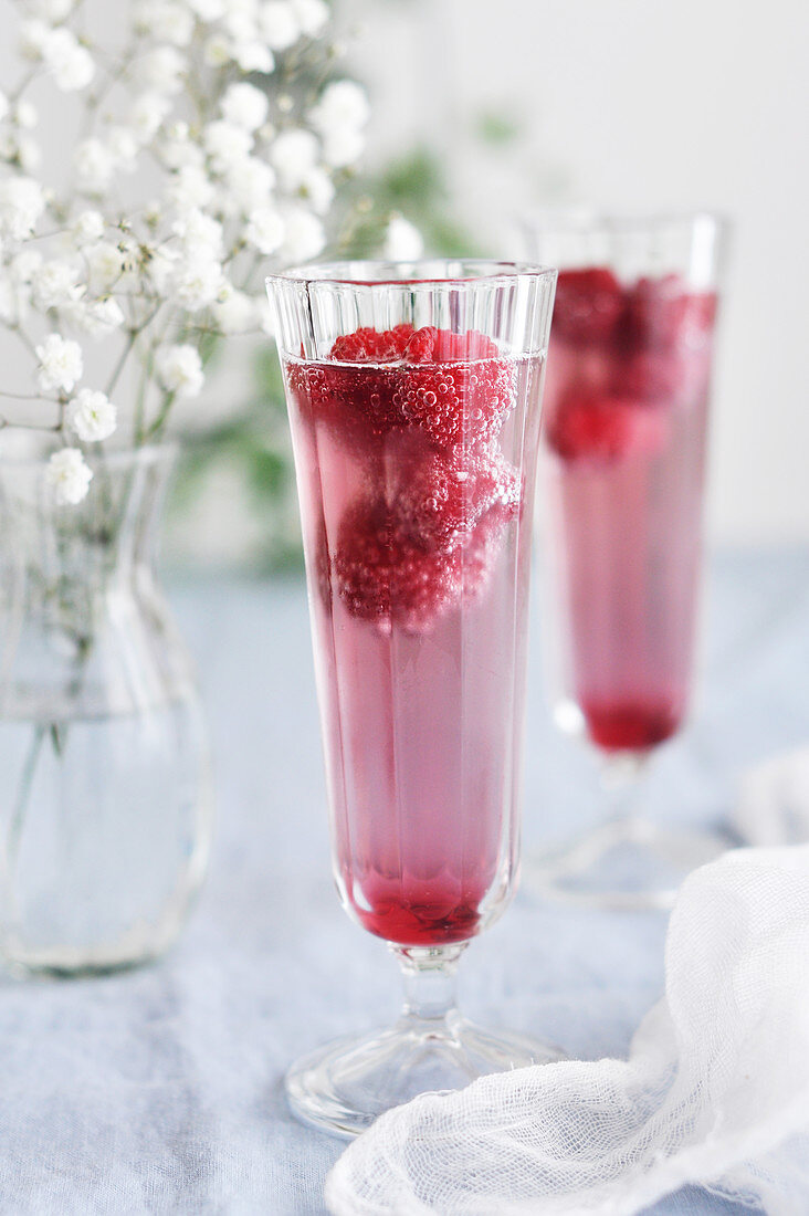 Zwei Gläser Granatapfelschorle mit frischen Himbeeren