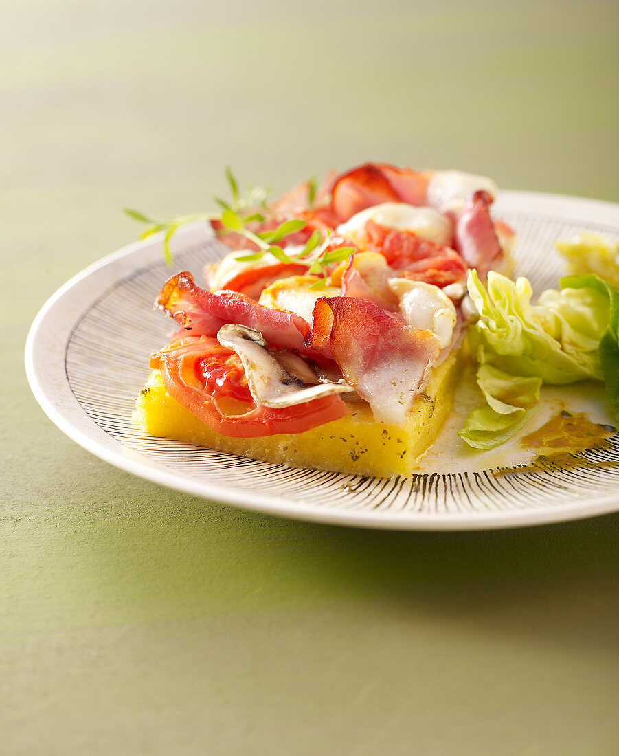 Polenta-Pizza mit geräuchertem Bauchfleisch, Tomaten, Champignons und Ziegenkäse